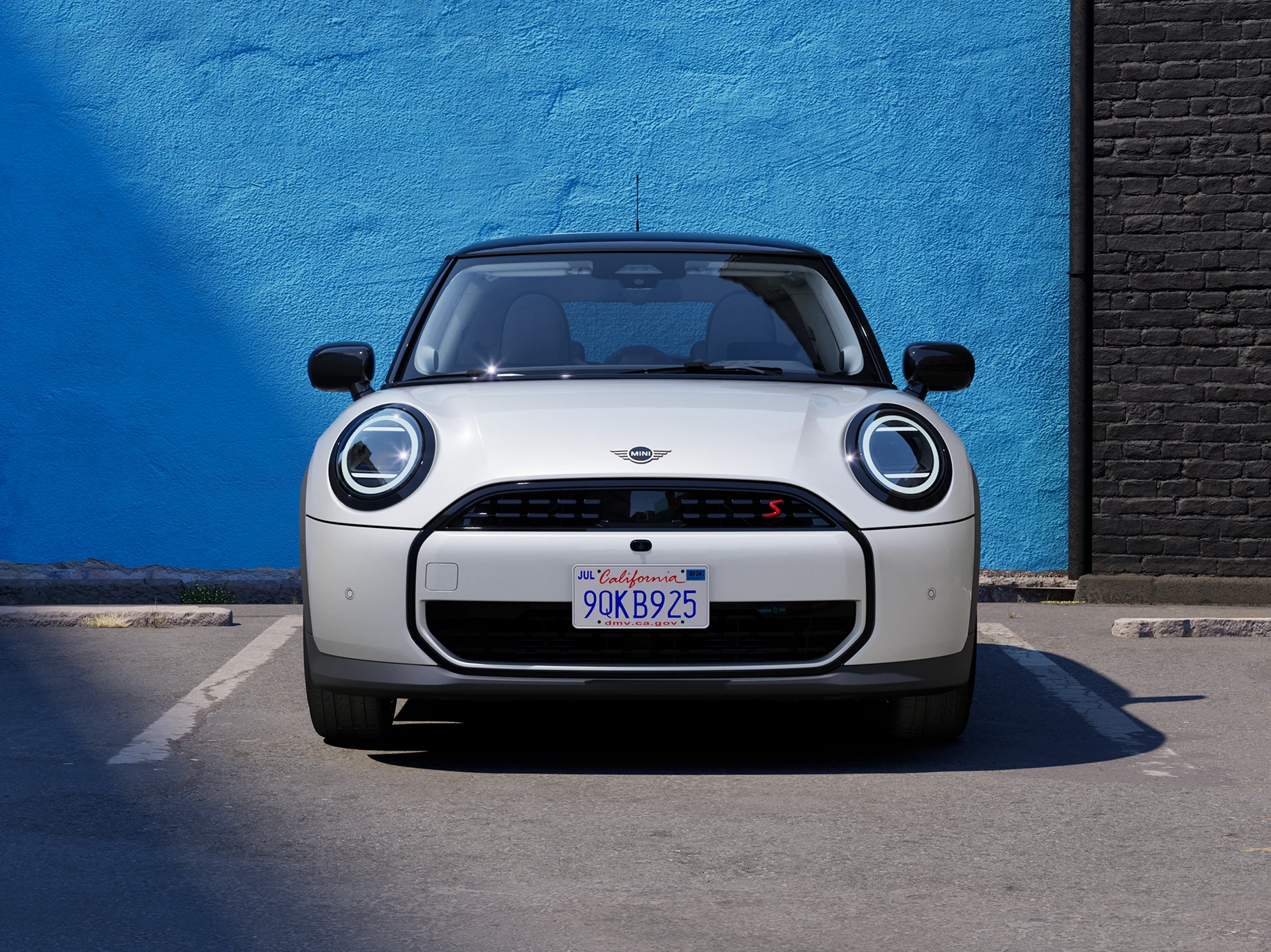 Поглед од предниот дел на MINI Cooper во Nanuq White со црн покрив паркиран.