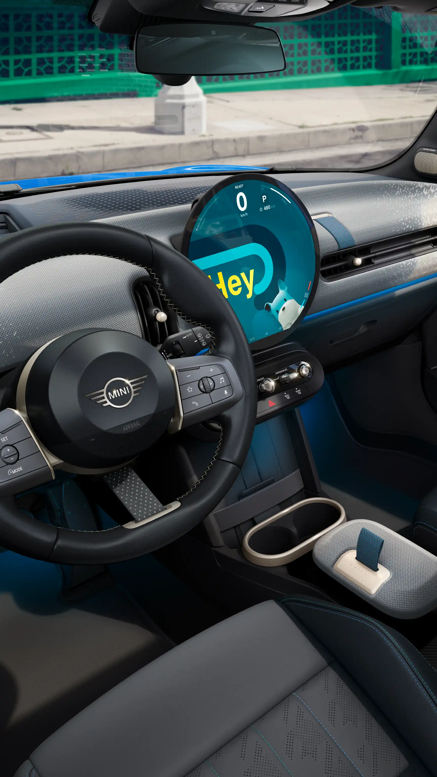 MINI interior with circular digital display showing a greeting interface and the steering wheel in the foreground.