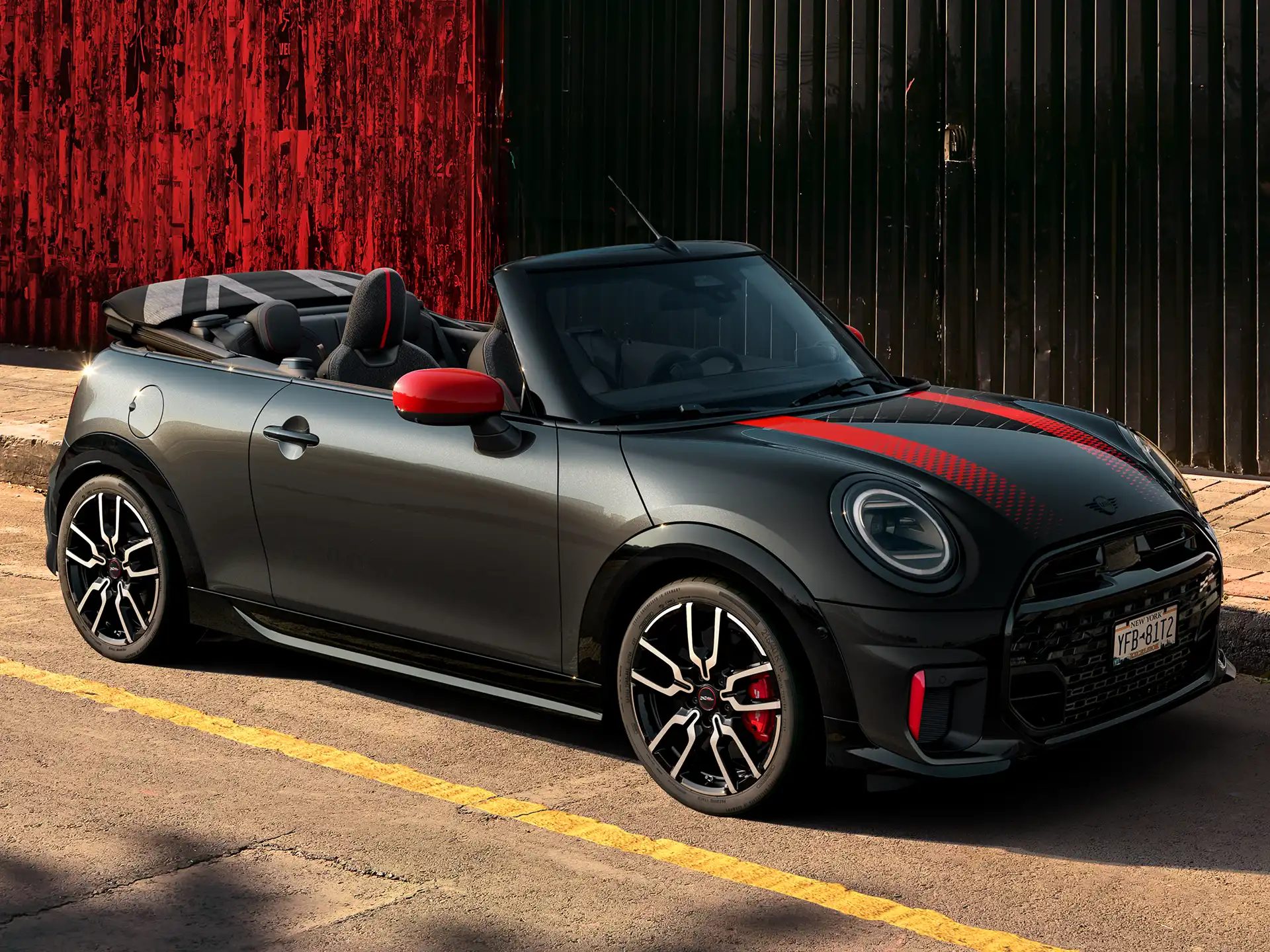 MINI Convertible John Cooper Works in Midnight Black II with Chili Red accents parked on an urban street with the roof down.