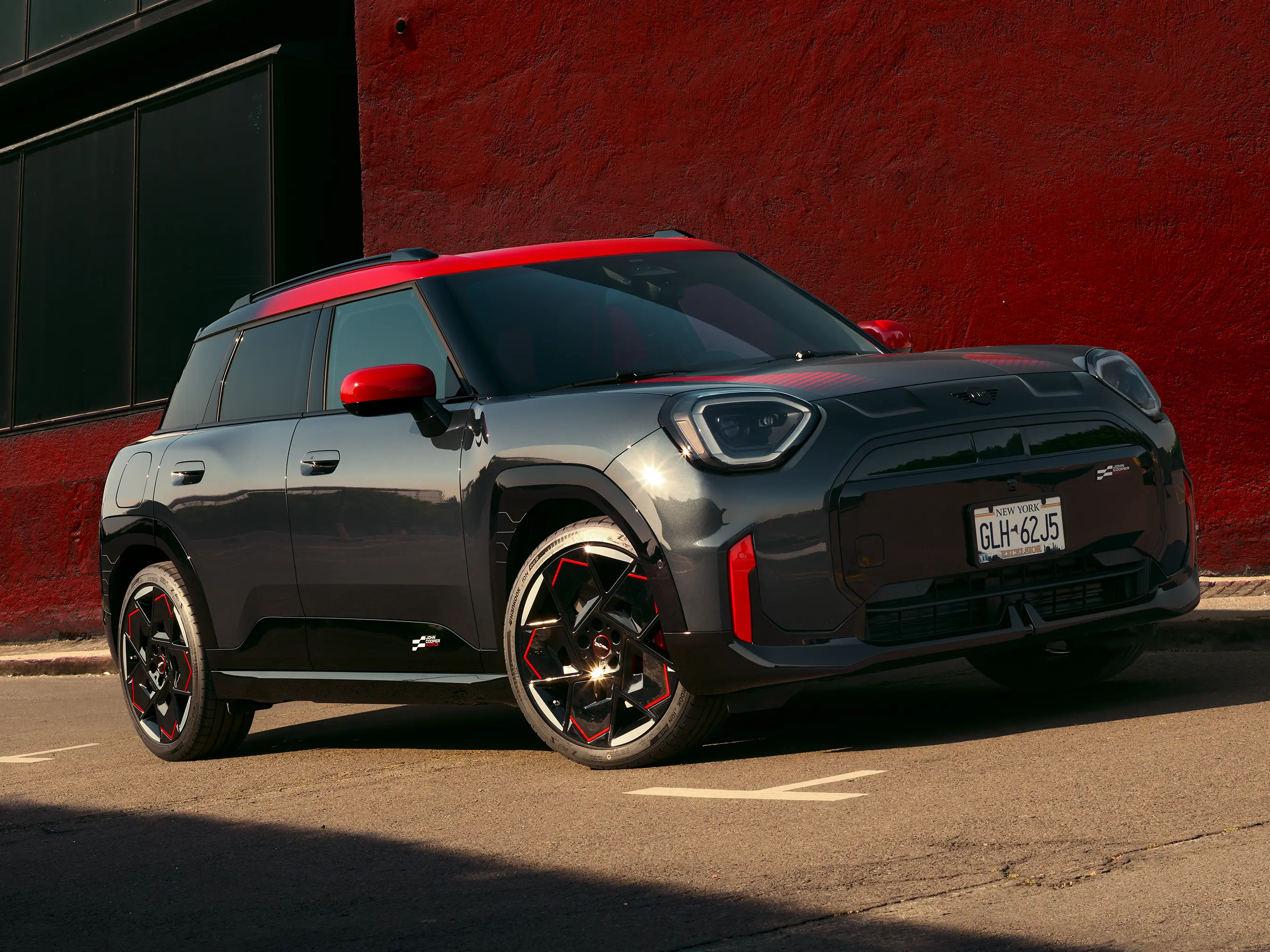 MINI Countryman John Cooper Works in Midnight Black II with Chili Red roof parked on an urban street.